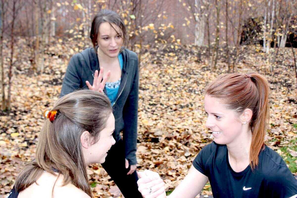 A personal trainer with two clients in a park